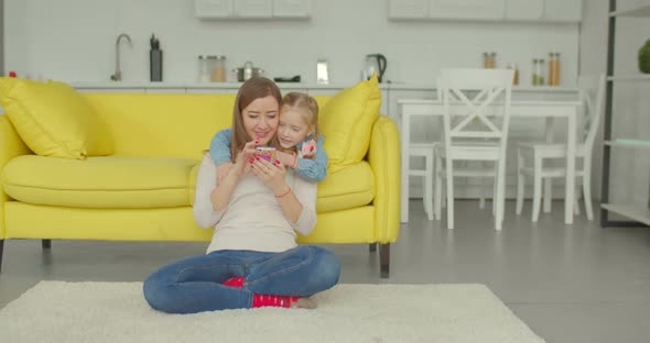 Joyful Mum and Daughter Watching Cartoons on Phone