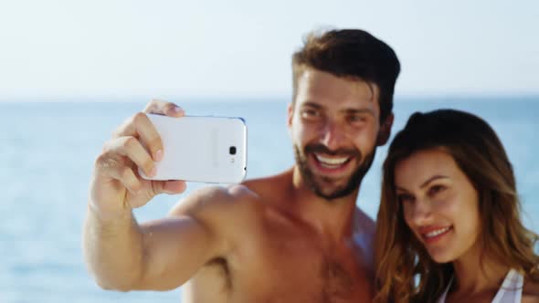 Couple taking selfie with mobile phone at beach