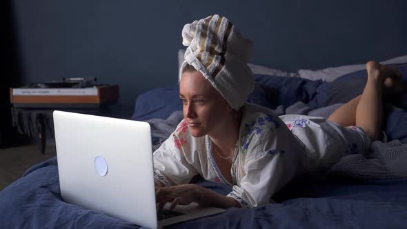 Woman Lying on Bed and Typing on Laptop Akspb