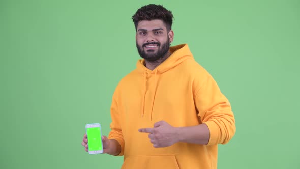 Happy Young Overweight Bearded Indian Man Showing Phone and Giving Thumbs Up