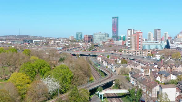 Drone shot towards central Croydon passing over green tram