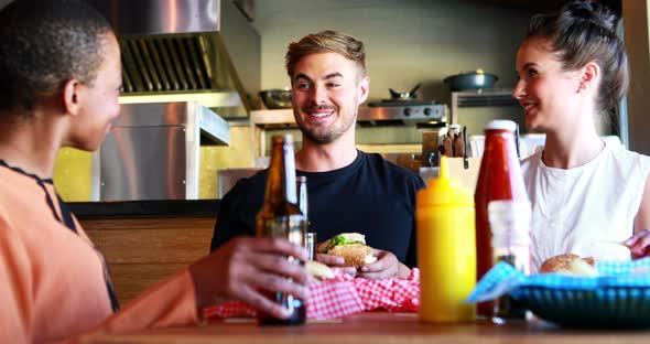 Friends eating burger while having beer