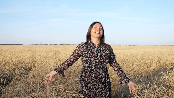 Young Woman in Dress Walks and Twirls Smiling in a Field of Ripe Wheat