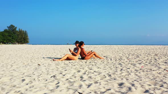 Beautiful beauty models travelling spending quality time at the beach on clean white sand and blue