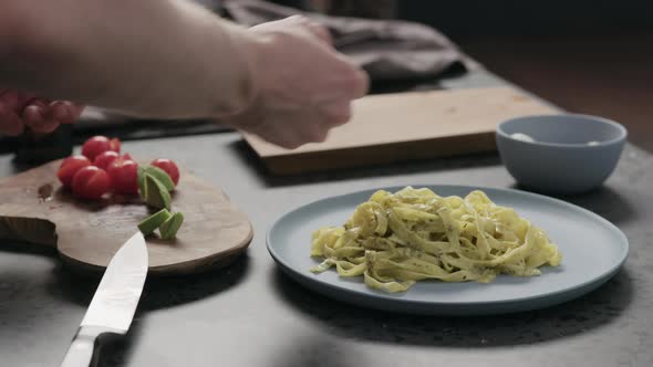 Slow Motion Man Add Avocado to Pesto Fettuccine on Blue Plate