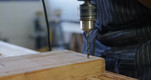 Carpenter drilling wooden plank with machine in workshop 4k