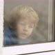 Little blond boy looking out the window while snowfall outside - VideoHive Item for Sale