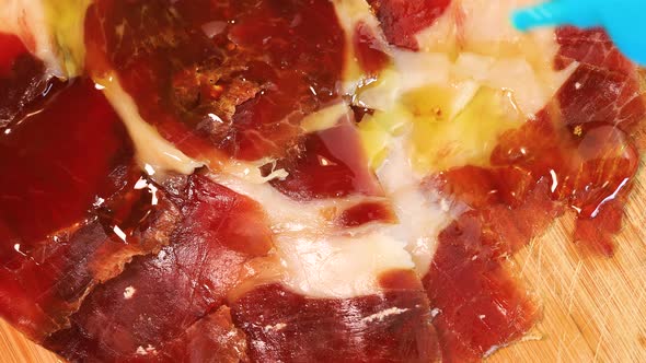 Olive oil poured on high quality serrano ham, macro shot. Close up view from above.