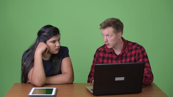 Young Multi-ethnic Business Couple Together Against Green Background