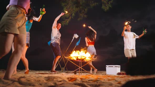 Group of Asian young man and woman having party on the beach at night.