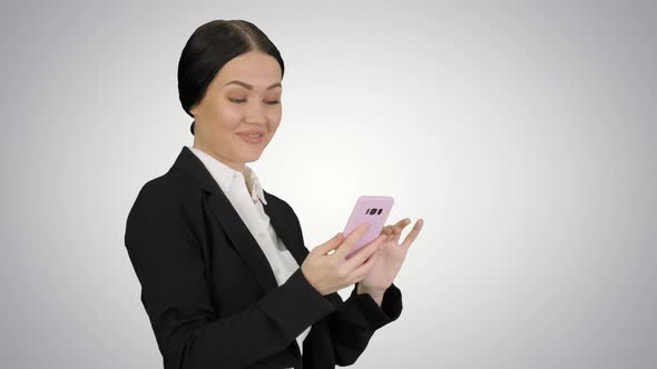 Smiling Businesswoman Checking Photos on Her Phone on Gradient Background