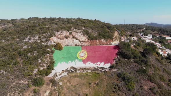 Portuguese Flag mural painting in Alte town, in Loulé, Algarve, Portugal - Wide dronie Aerial shot