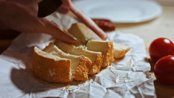 Closeup of Hand Cutting French Cheese Marquis Castello