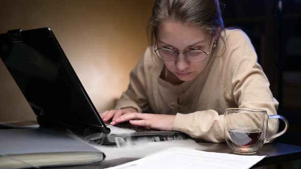 A young woman's old laptop starts to smoke while she is working