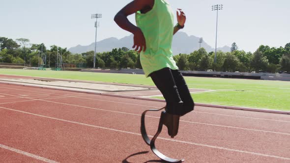 Disabled mixed race man with prosthetic legs running on race track and stopping