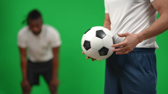 Young Unrecognizable Caucasian Man Standing on the Right Passing Football Ball in Hands with Blurred