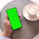 Man holding smartphone with vertical green screen and drinking coffee. - VideoHive Item for Sale