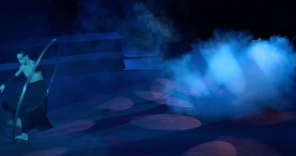 Young Man Is Spinning and Walking in a Wheel on Stage of a Circus