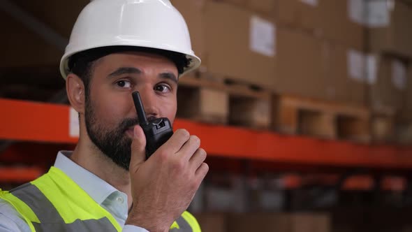 Warehouse Engineer Using Radio and Tablet at Work