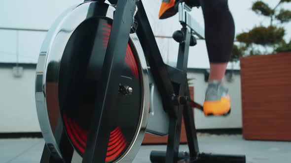 Healthy Caucasian Woman Exercising Workout on Stationary Cycle Machine Bike on House Rooftop Gym