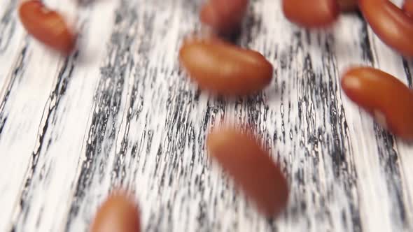Red Kidney Beans fall on a wooden texture table. 