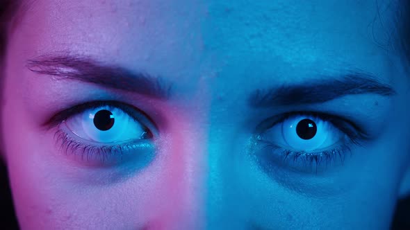 Closeup of Blinking of Eyes Wearing White Lenses in Ultraviolet Light Scary Look in Neon Blue Light