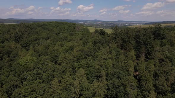 Aerial footage of fields and thick deciduous trees in the countryside of west germany in summer