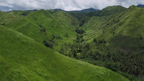 Flight over Green Grassy Rocky Hills