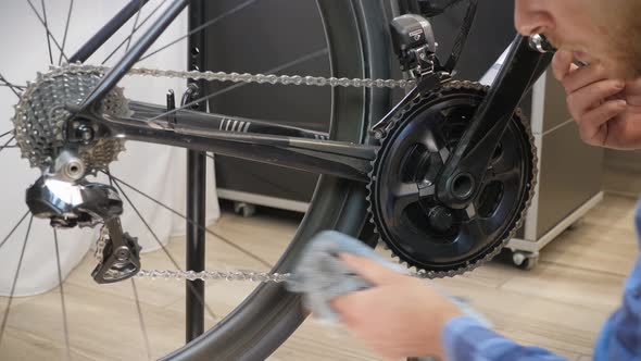 Bike maintenance. Bicycle mechanic cleaning bike chain with microfiber cloth.