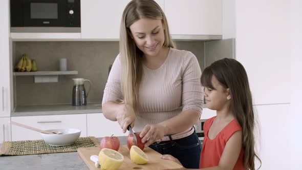 Joyful Mom Cutting Fresh Apples in Kitchen