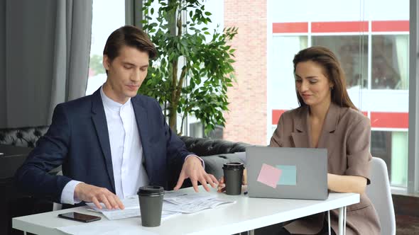 Beautiful young woman working in office with her colleague and they are drinking coffee