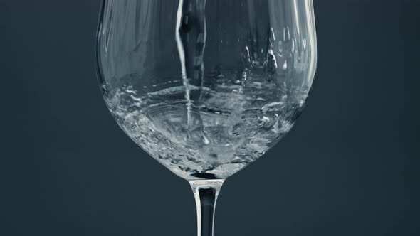 Sparkling Water Pouring Glass at Dark Background Closeup