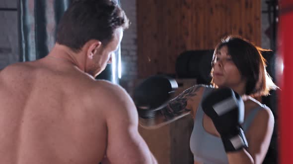 Boxing Training in the Gym Woman Boxer Training Her Punches on Punching Bag with Her Male Trainer