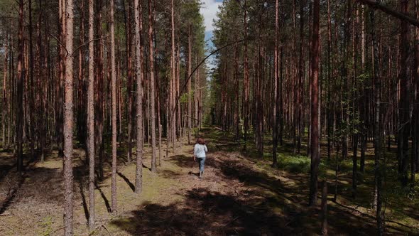 Happy Woman Runs Along Sunny Cut Path Clearing in Pine Forest