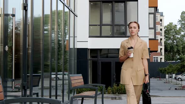 Young Woman texting Messages on Smartphone and drinking Coffee to go while the Walk. Success