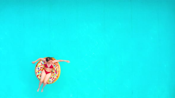 Aerial View of a Woman in Red Bikini Lying on a Donut in the Pool