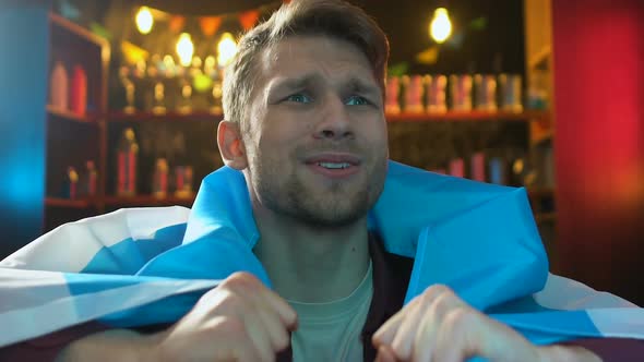 Sad Male Fan Holding Argentina Flag in Bar, Disappointed About Team Losing