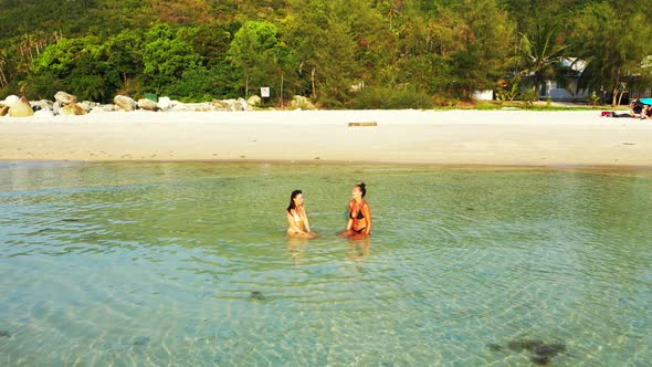 Ladies together best friends on beautiful seashore beach trip by transparent ocean and white sandy b