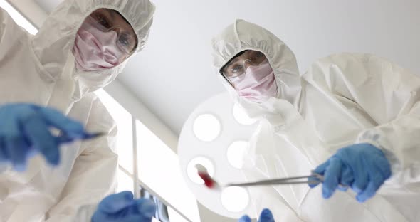 Surgeons in Protective Suits and Goggles Performing Surgery on Infectious Patient Bottom View Movie