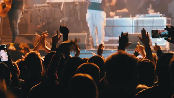 Crowd of People at a Rock Concert Raises His Hands Up and Applauds Fans