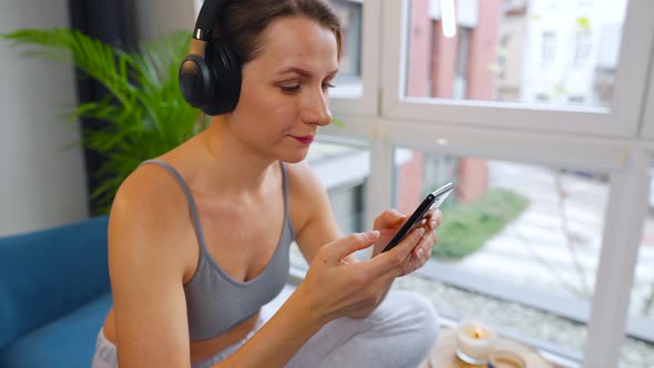 Woman in Wireless Headphones Listening to Music and Using Mobile Apps or Communicates on Social