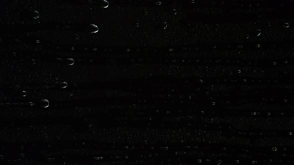 Closeup Water Rainfall Rain Drops Falling on Window Glass Over Black Background