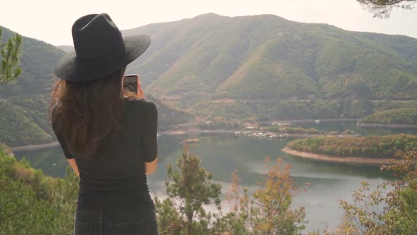 Young Woman Taking Photos of Mountain Lake