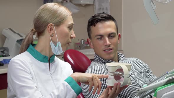 Handsome Man Showing Thumbs Up Sitting in Dental Chair, Talking To His Dentist