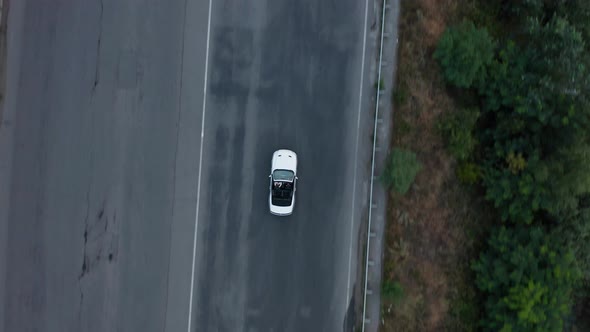 Aerial drone shot of a car driving on a bridge.