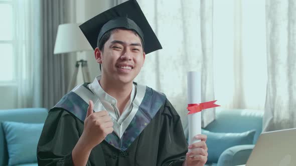 Excited Asian Man Holding A University Certificate, Smiling And Thumb Up To Camera