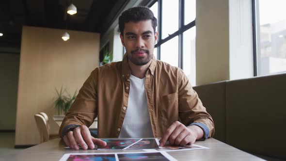 Mixed race businessman having a video chat going through paperwork in a modern office