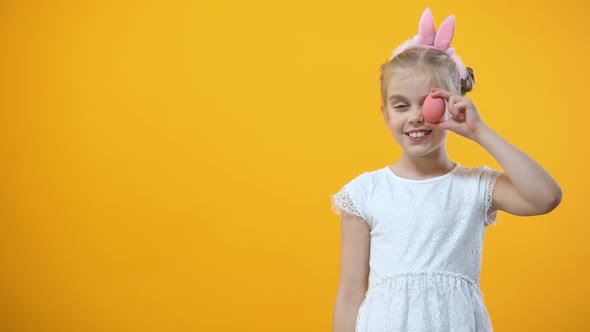 Playful Female Kid Holding Colored Egg in Front of Eye, Easter Symbol, Holiday