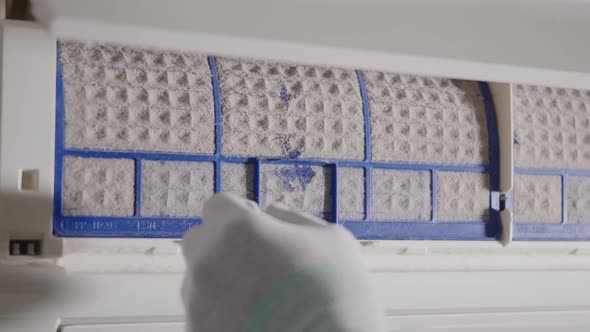 Hand of technician man working pulling dusty filter from air conditioner