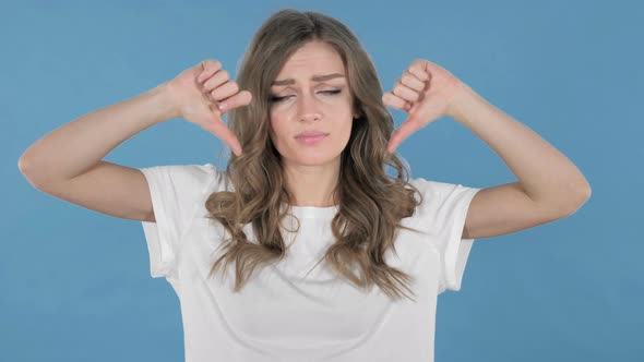 Young Girl Gesturing Thumbs Down Isolated on Blue Background